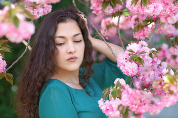 Fototapeta premium beautiful girl posing near sakura flowers as background, face closeup, springtime