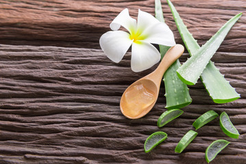 aloe vera gel on wooden spoon with aloe vera on wooden table
