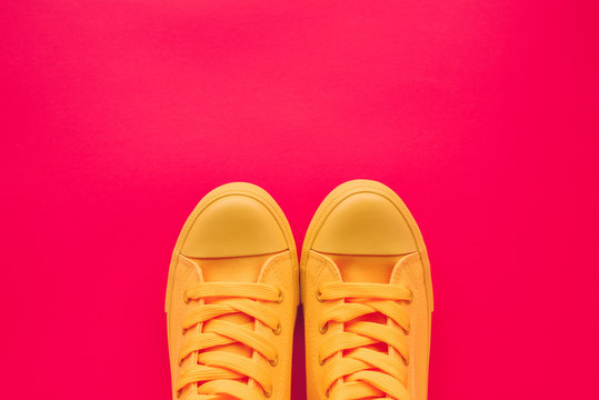 Yellow canvas shoes sneakers on neon pink background