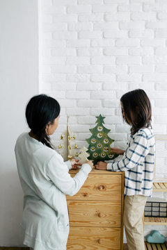 Asian mother and son decorating home with Christmas ornament