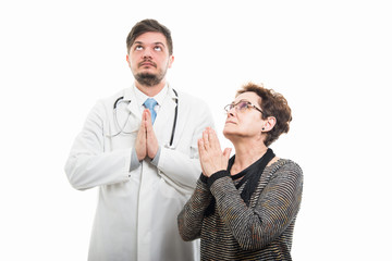 Female senior patient and male doctor praying together