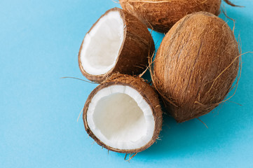 Whole and halfs of coconuts on a blue background. Close up.