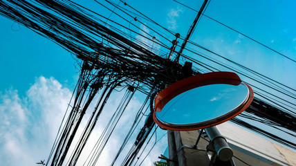 Convex Mirror with Orange Cap and Tangle Electric Wires from Low Angle View - Bright Clear Sky