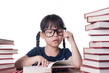 The girl is reading a book at the table.