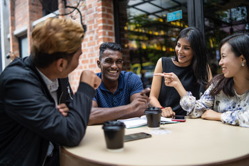 a group of asian multiculture friends discussing work at cafe