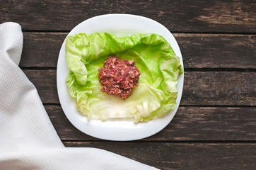 Cabbage roll on the white plate. Raw minced pork with beef in cabbage green leaves.