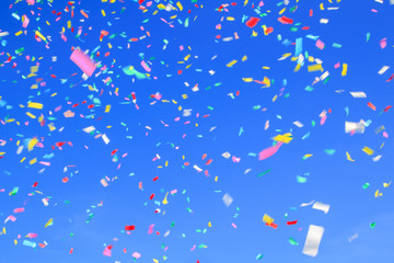 multicolored confetti on clear blue sky background. Concept of holiday backdrop