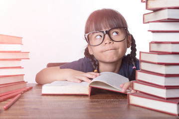 The girl is reading a book at the table.