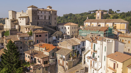 Naklejka premium Aerial view of Castelnuovo di Porto castle, near Rome in Italy. The building has a square shape with four towers at the corners. On the facade there is a clock and around the houses of the village.