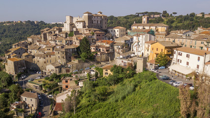 Fototapeta na wymiar Aerial view of the village of Castelnuovo di Porto, near Rome, in Italy. The village is built perched on a hill and overlooks a green valley full of trees. At the top there is the medieval castle.