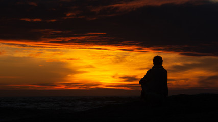 Naklejka na ściany i meble Sitting on the beach watching the sun set