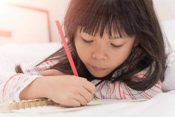 little girl lying on the bed and reading a book