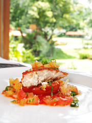 Fried fish with tomato on white plate