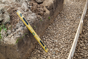 professional level and trench with rubble and formwork, which is prepared for pouring the foundation