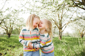 Little twins hug and laugh.