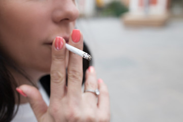 Smoking woman with a thin cigarette close-up