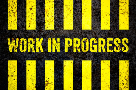 Work in progress warning sign with yellow and black stripes painted over cracked concrete wall coarse texture background. Concept for do not enter the area, caution, danger, construction site.