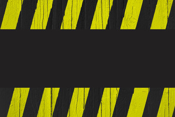 Warning sign with yellow and black stripes painted over cracked wood as border frame with black empty background space for text in the center of the frame.