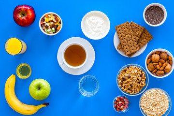 Make a menu for wholesome breakfast. Fruits, oatmeal, yogurt, nuts, crispbreads, chia on blue background top view