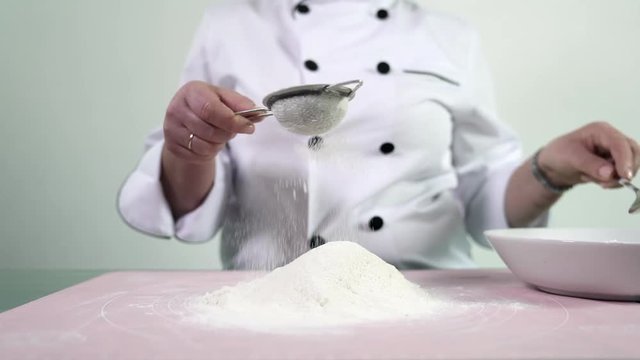 Cake preparation art. Famous baker whipping flour using a bolter. Heap of wheat flour is ready for kneading dough