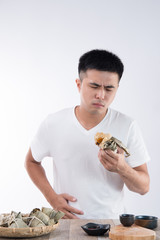 A man has a stomachache after eating delicious zongzi(rice dumpling) on Dragon Boat Festival, Asian traditional food, white background