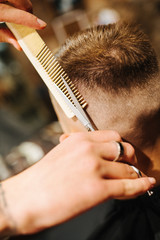 Hairdresser blow drying his client in barbershop. Barber using scissors and comb
