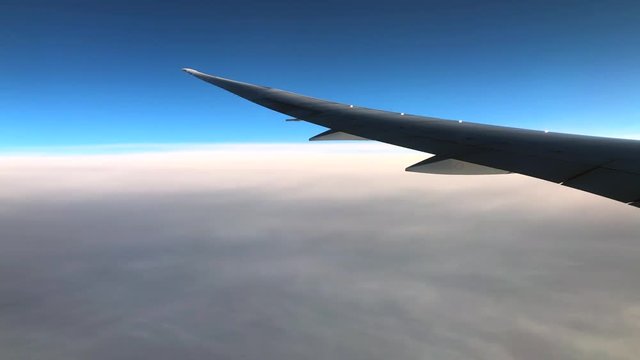 The Wing of Plane and view of clouds through window of an airplane on a sunny day