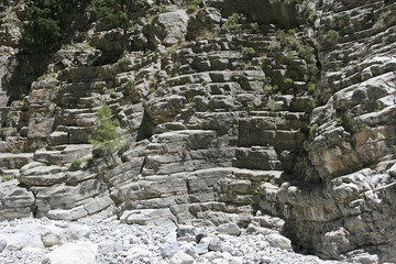 The high beautiful steep rocky slope of the gorge with stony steps on the sunny day