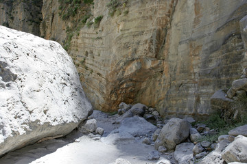 The beautiful rocky wall with horizontal stone lines, the small path and the big white stone in the...