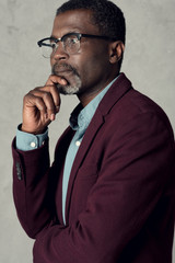 portrait of thoughtful african american man in eyeglasses and burgundy jacket