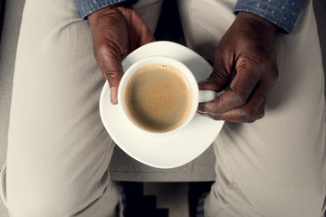 partial top view of african american man holding cup of coffee
