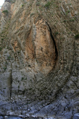 The high beautiful steep rocky slope of the gorge with folds as the vertical arc on the sunny day.