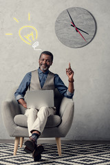 executive african american businessman with laptop having idea and pointing up, with light bulb sign