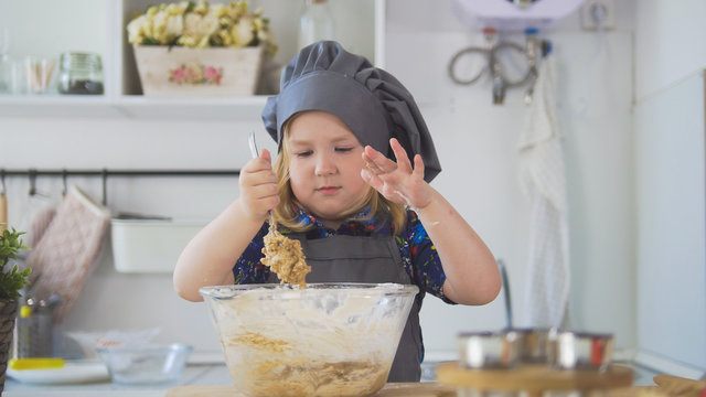 Girl baker mixes the mixture for cookies with a big spoon