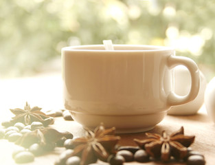 cup of coffee and beans with blurred green leaf background