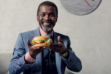 cheerful middle aged african american man with hamburger