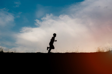 Attractive fit man running fast along big modern bridge at sunset light, black man doing workout outdoors, silhouette runner in windbreaker jogging over bridge road with amazing sunset on background