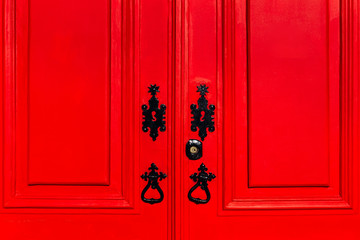 close-up door with a bright red color with black metallic accessories and keyhole