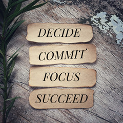 Motivational and inspirational quote - ‘Decide, commit, focus, succeed’ written on pieces of...