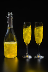 close up view of bottle and glasses of yellow champagne on black background