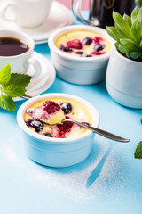 Berry clafouti. Traditional french sweet fruit dessert clafoutis with raspberries and blueberries on blue background. Healthy gluten free food concept with copy space.