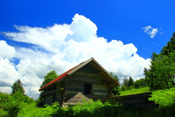 Old wooden house on mountain in Bosnia and Herzegovina, storm clouds on blue sky in background