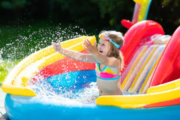 Child in garden swimming pool with slide
