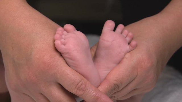 Baby's legs in the hand of an adult closeup