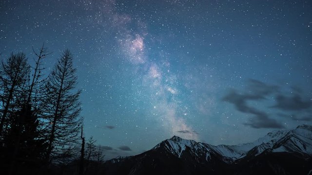 time lapse of Milky Way Galaxy stars over snow capped Mountains at a clear night