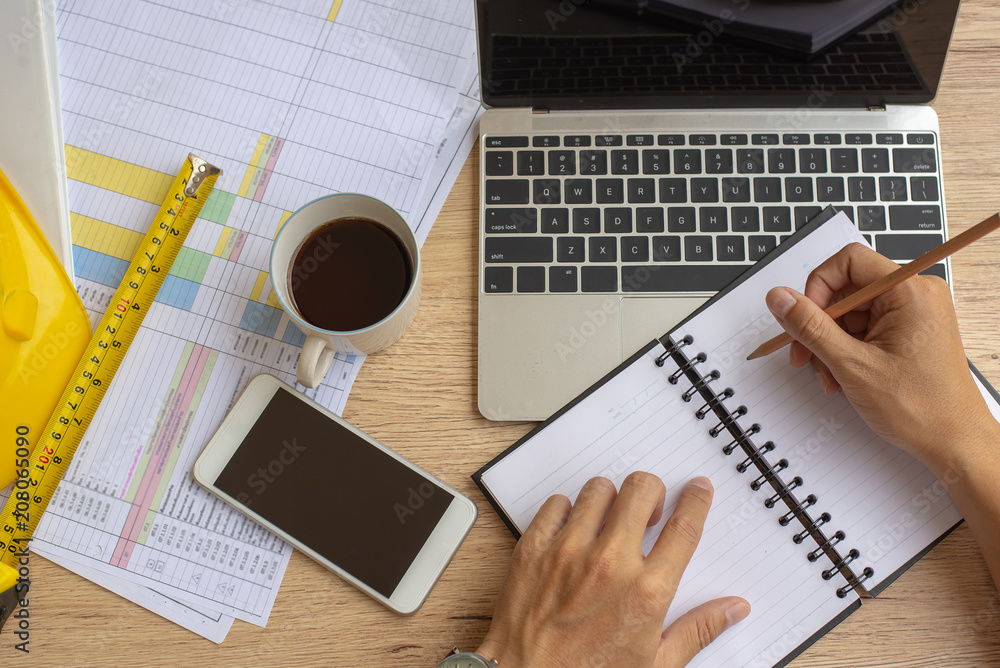 Poster top view,business man hand writing content or somethings on notebook with using laptop at wooden tab