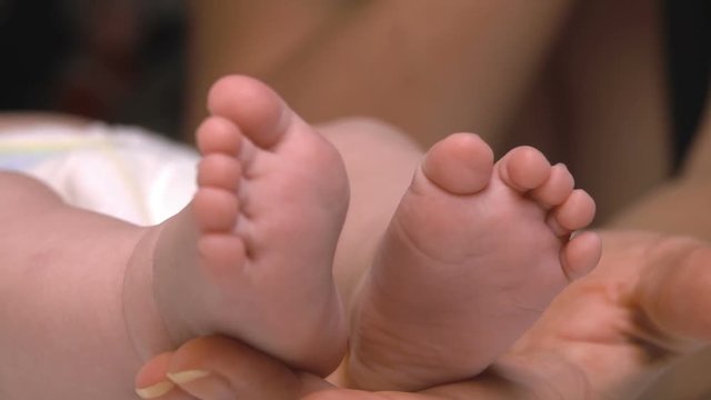 Baby legs on the palm of an adult closeup