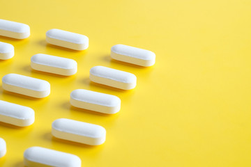 White pills on yellow background