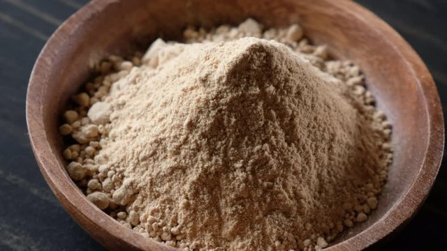 Rotating superfood maca powder in wooden bowl