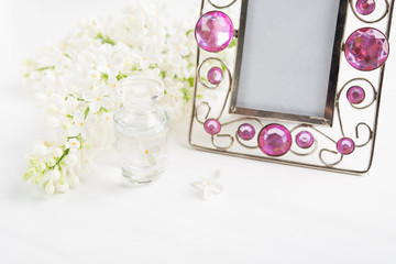 Obraz na płótnie Canvas Perfume bottle, white lilac and frame for photo